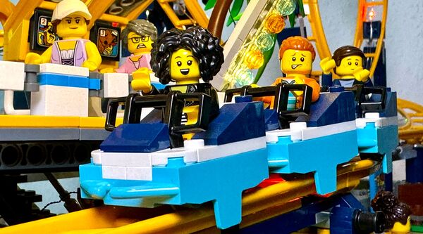 Nicole Angela Buck mit ihrer selbst gebauten LEGO® Achterbahn – Sinnbild für Innovation, Spaß und Teamwork im Business.